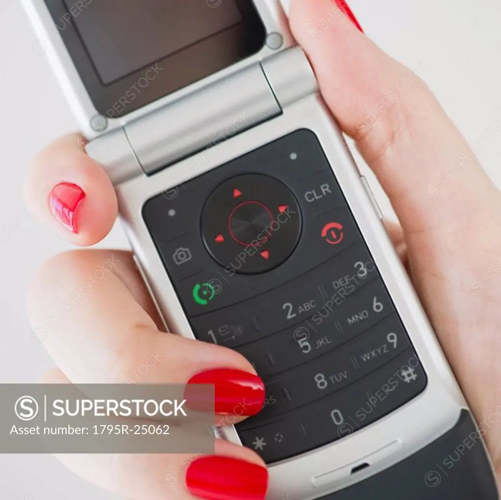 Woman wearing red nail polish holding a cellular phone