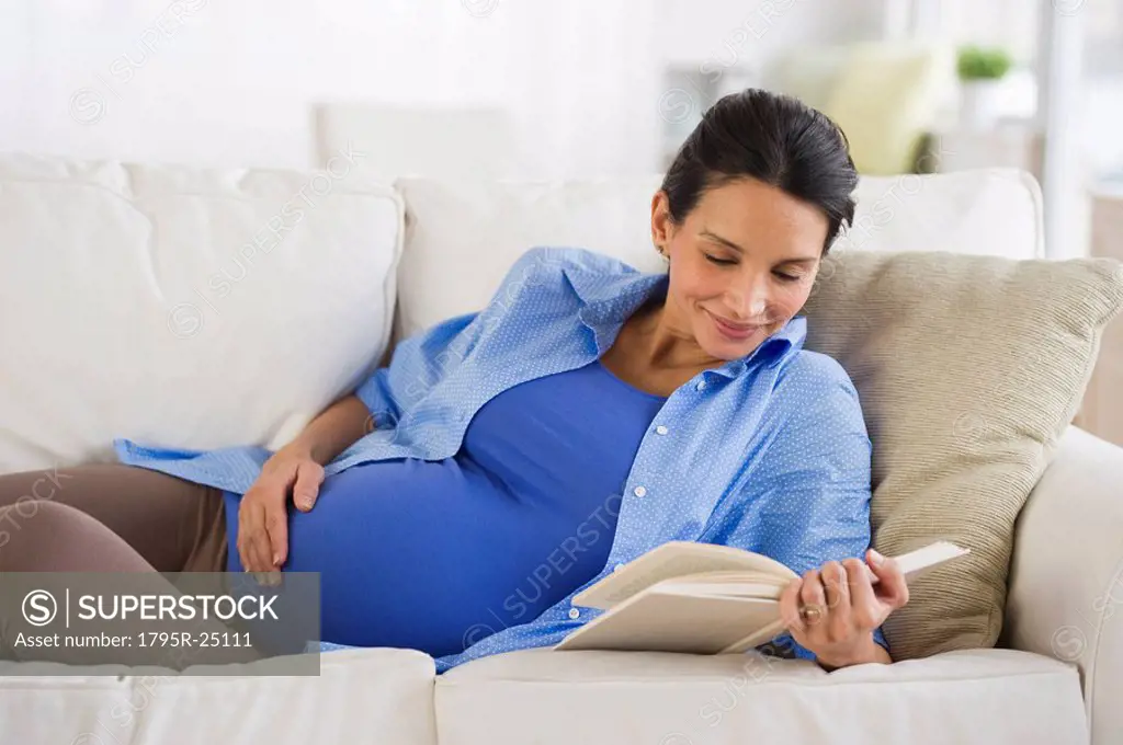 Pregnant woman reading on couch