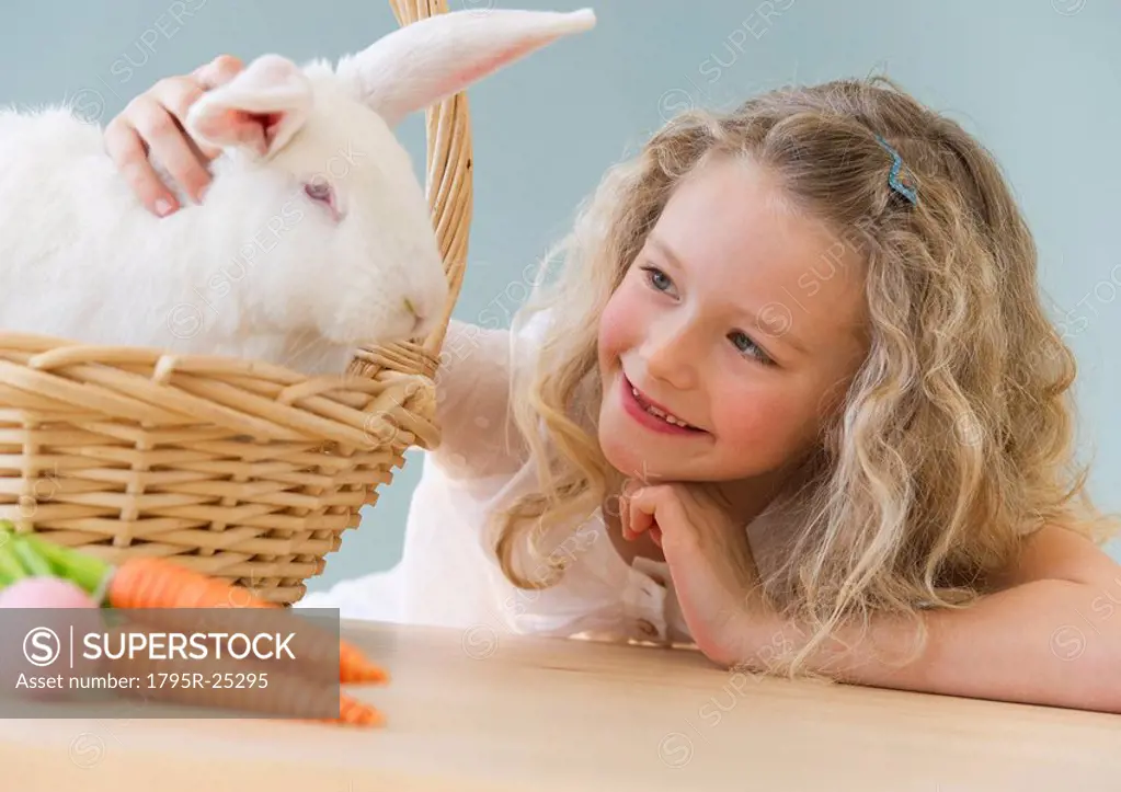 Young girl petting a rabbit in a basket