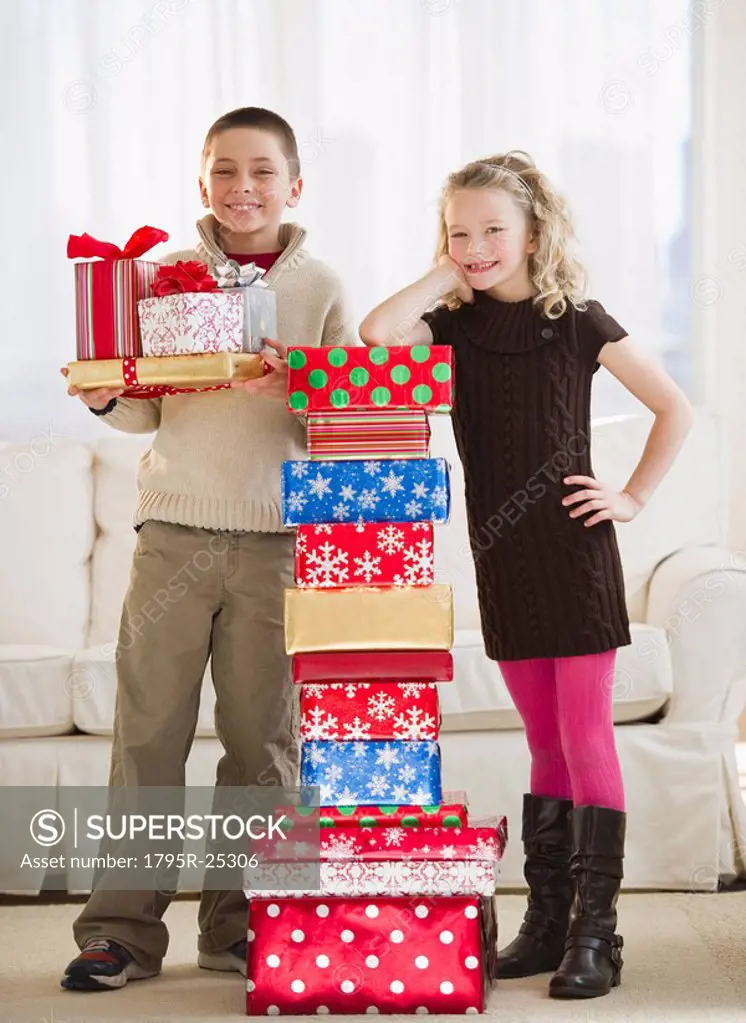 Young children beside a stack of Christmas gifts