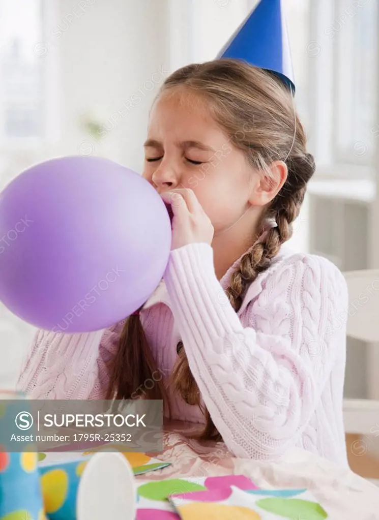 Young girl blowing up balloon
