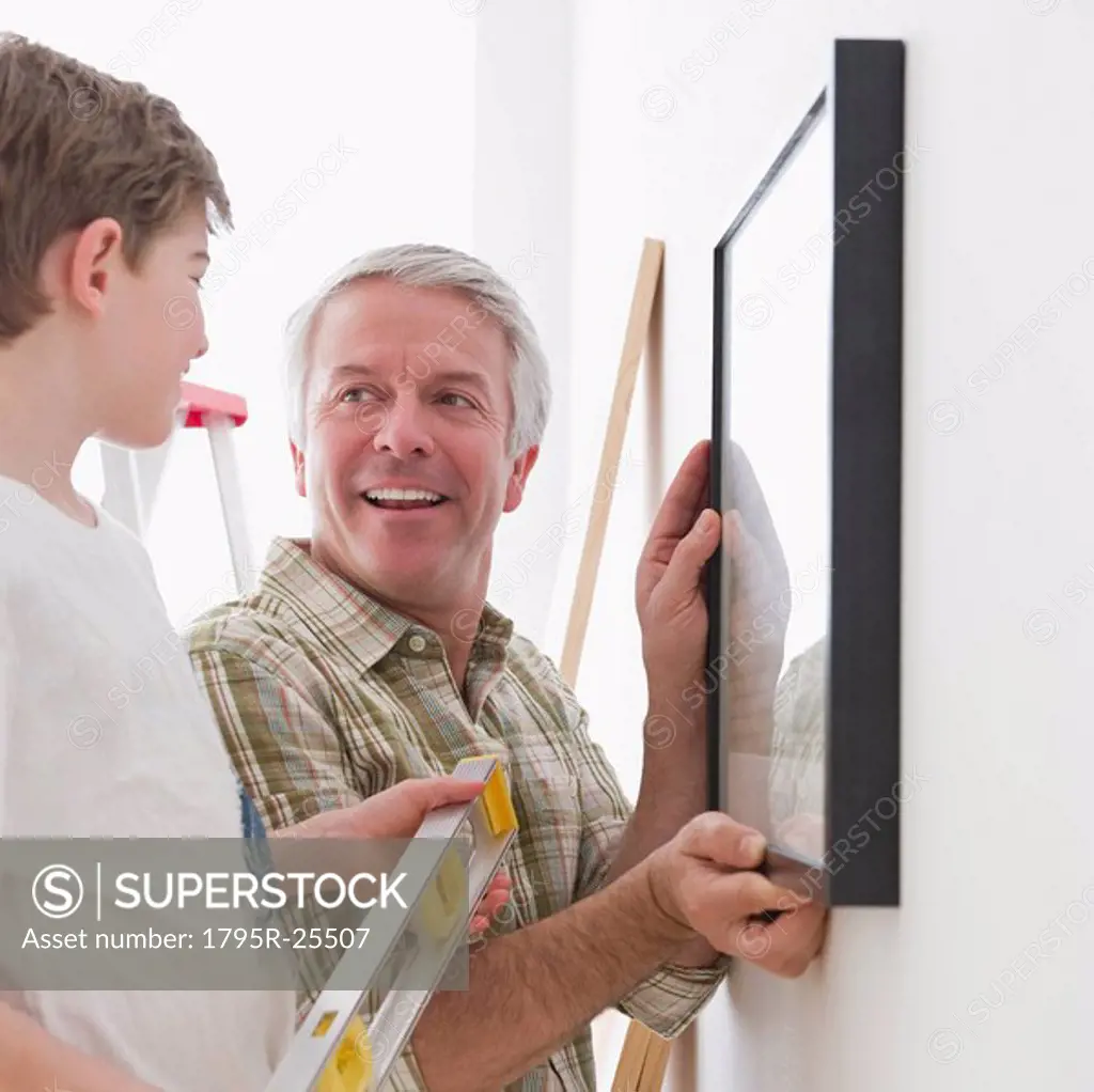 Father and son hanging picture on wall