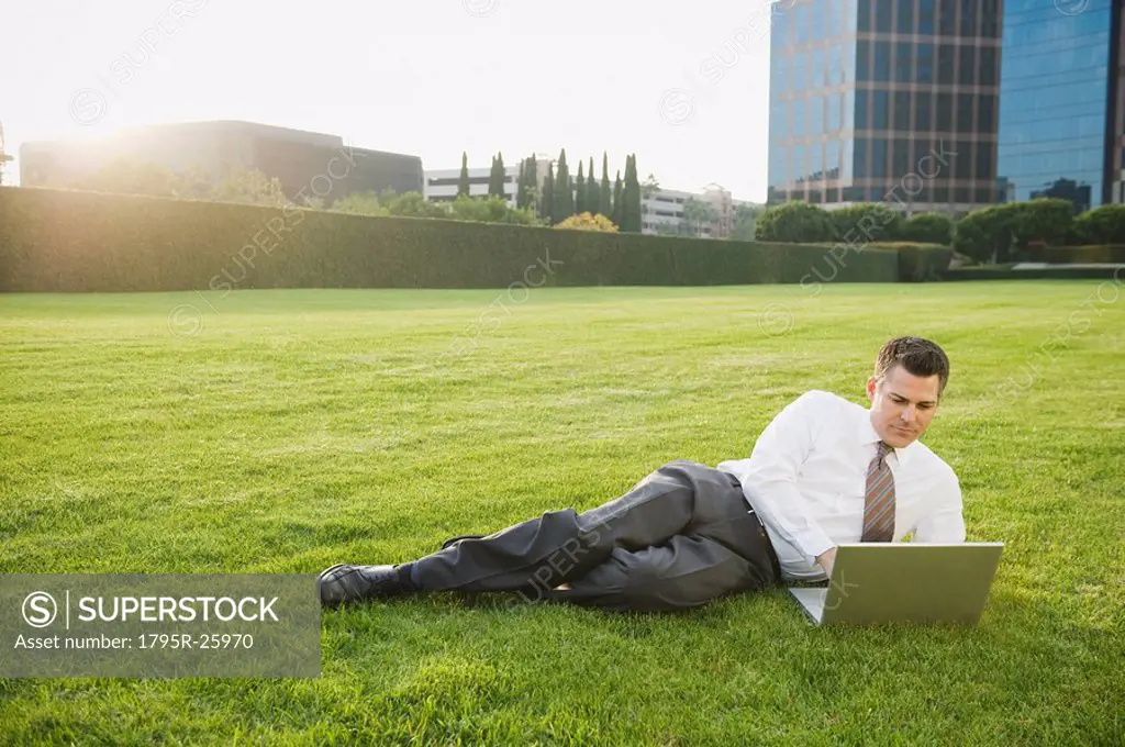 Businessman relaxing with laptop on lawn