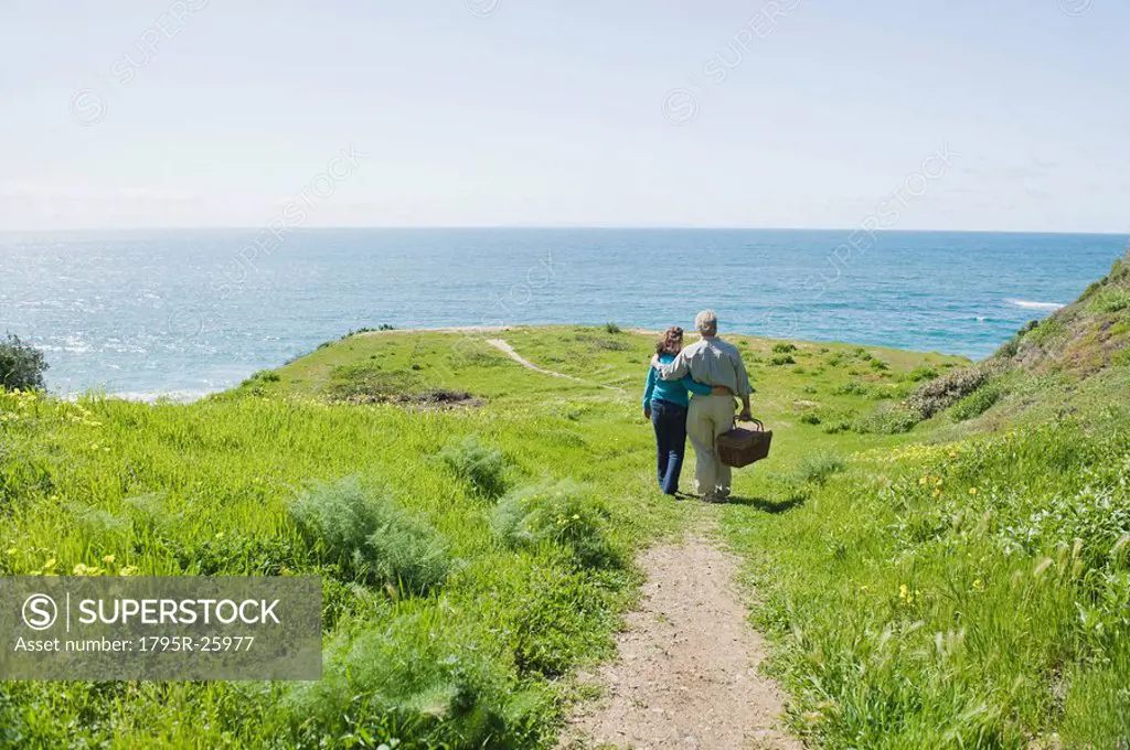 Couple carrying picnic basket to the beach