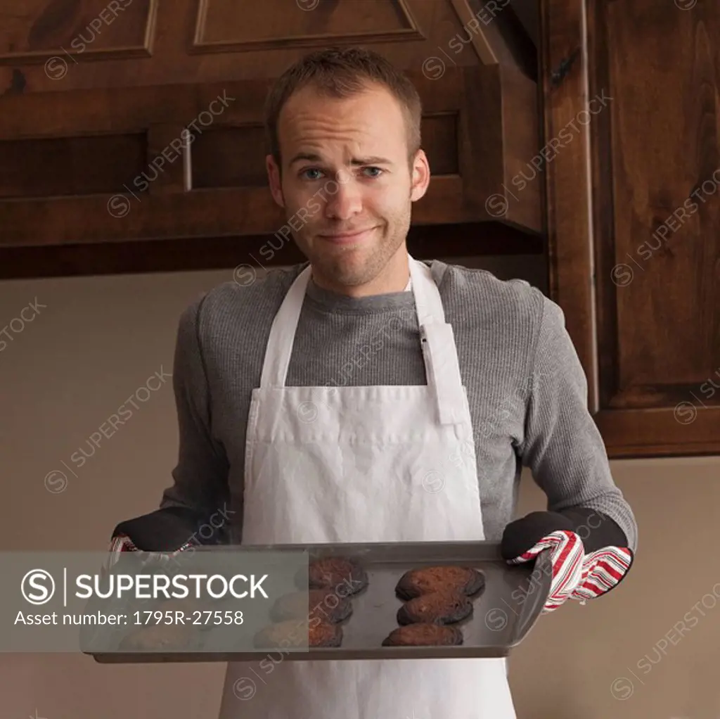 Man holding tray of burnt cookies