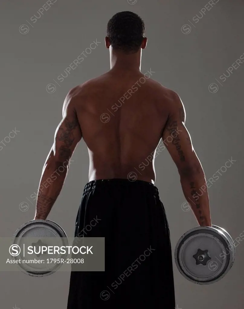 Physically fit man lifting dumbbells