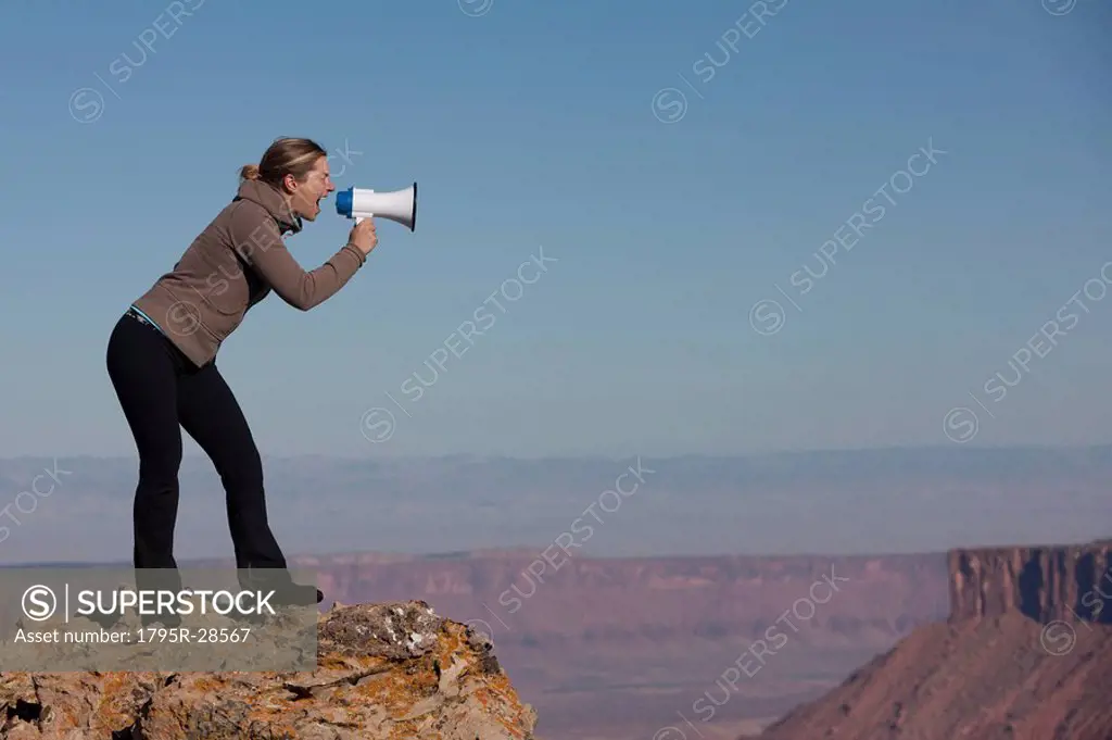 Woman yelling into megaphone at top of canyon
