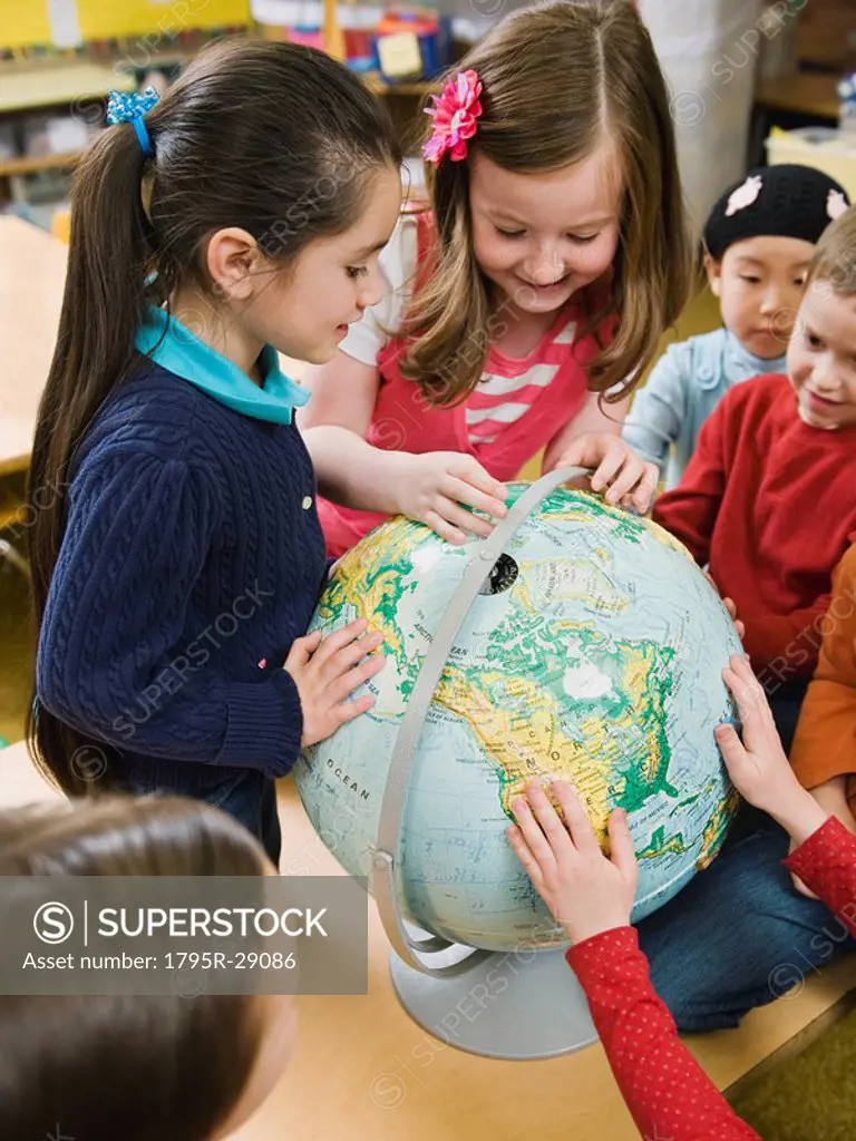 Kindergarten students looking at globe