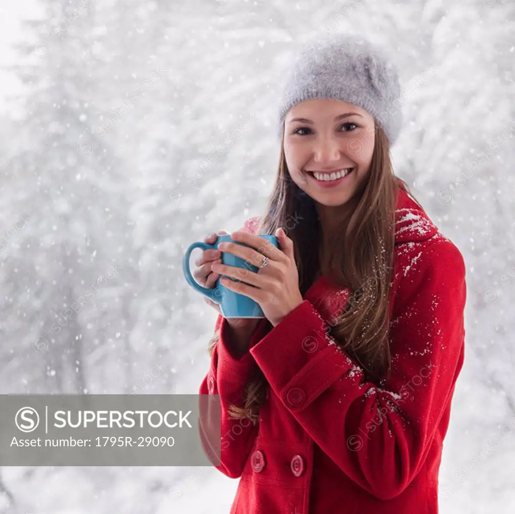 Woman in the snow holding a warm drink