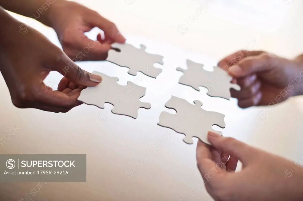 Four hands holding puzzle pieces