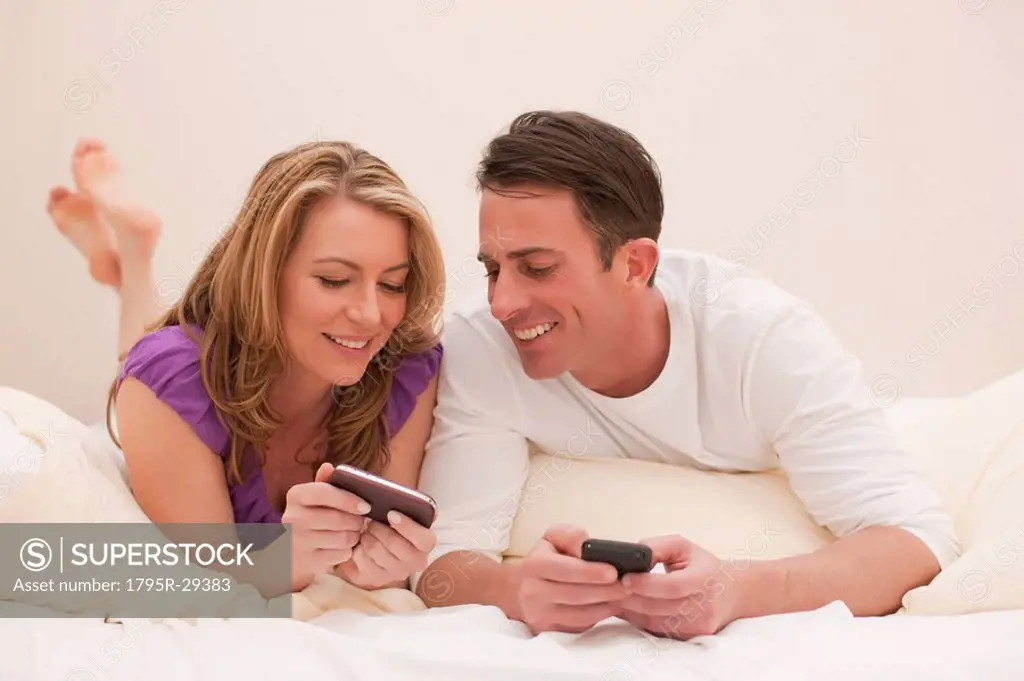 Couple looking at photo on cell phone will lying in bed
