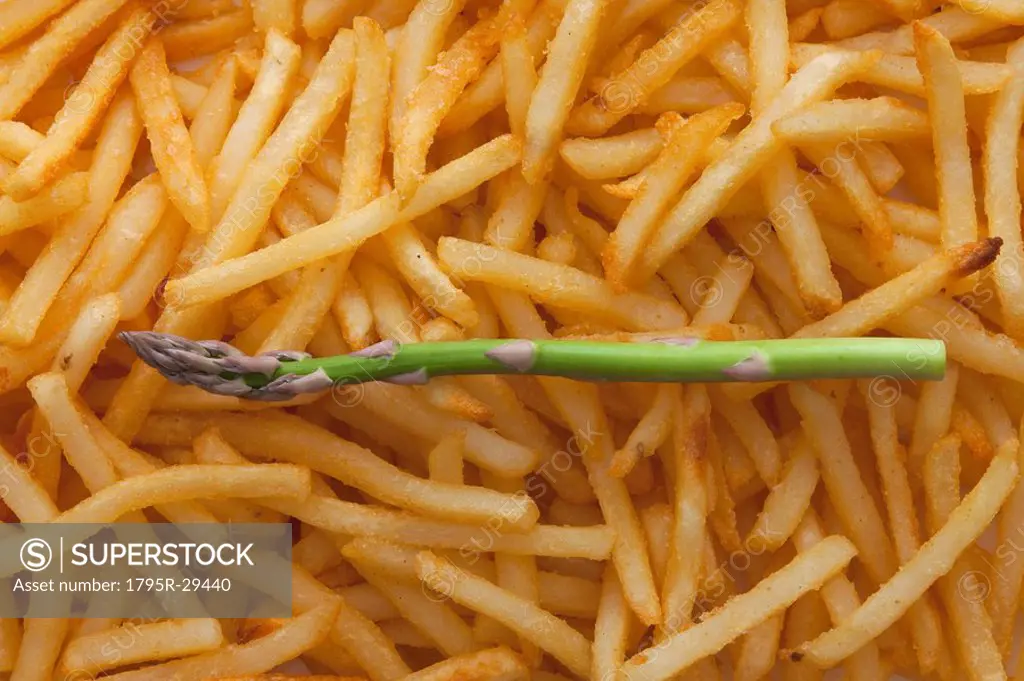 Asparagus spear on top of a pile of French fries