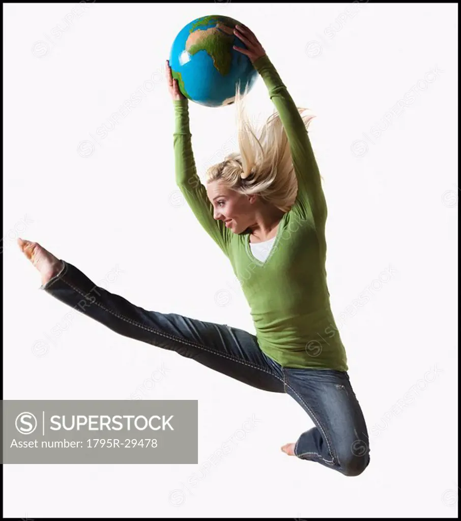 Woman jumping in air while holding globe