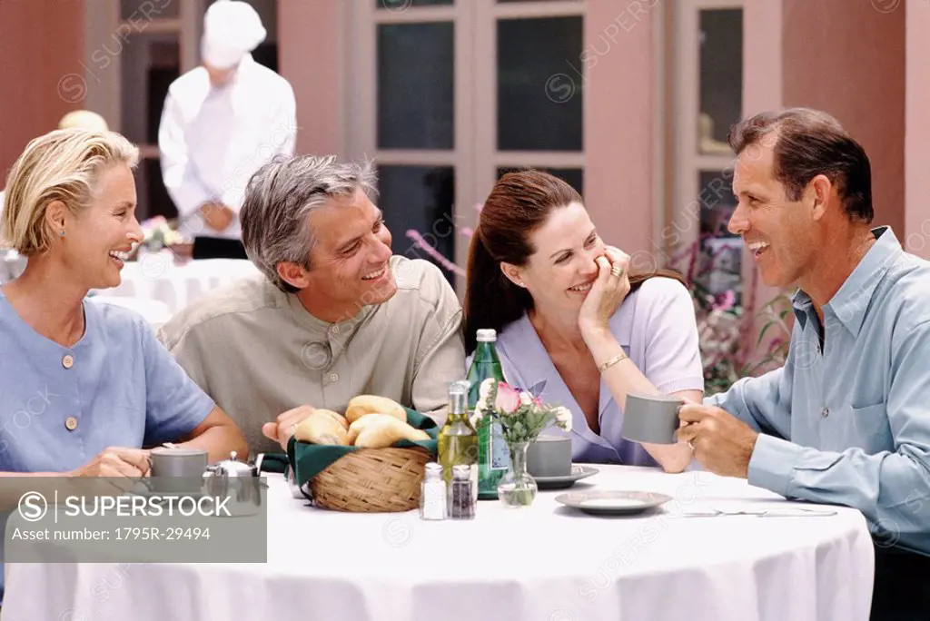 Two couples having dinner together on patio of restaurant