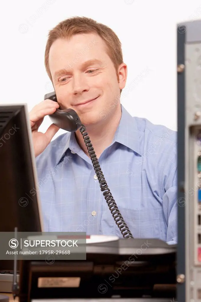 Businessman talking on phone while looking at computer