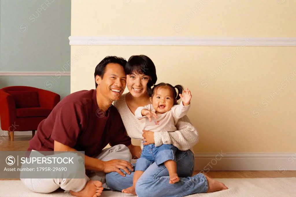 Happy parents sitting on the floor with their infant daughter