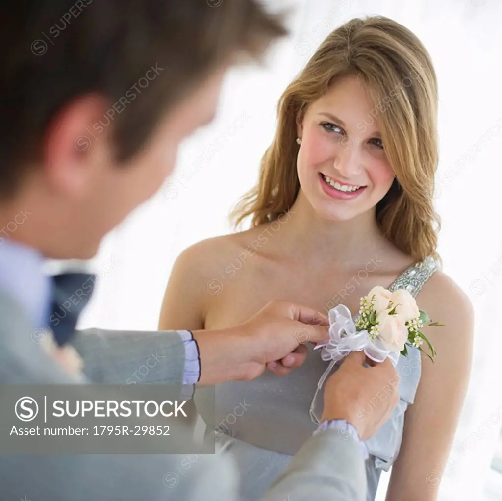 Man pinning corsage on his date´s prom dress