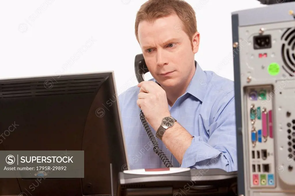 Businessman talking on phone while looking at computer