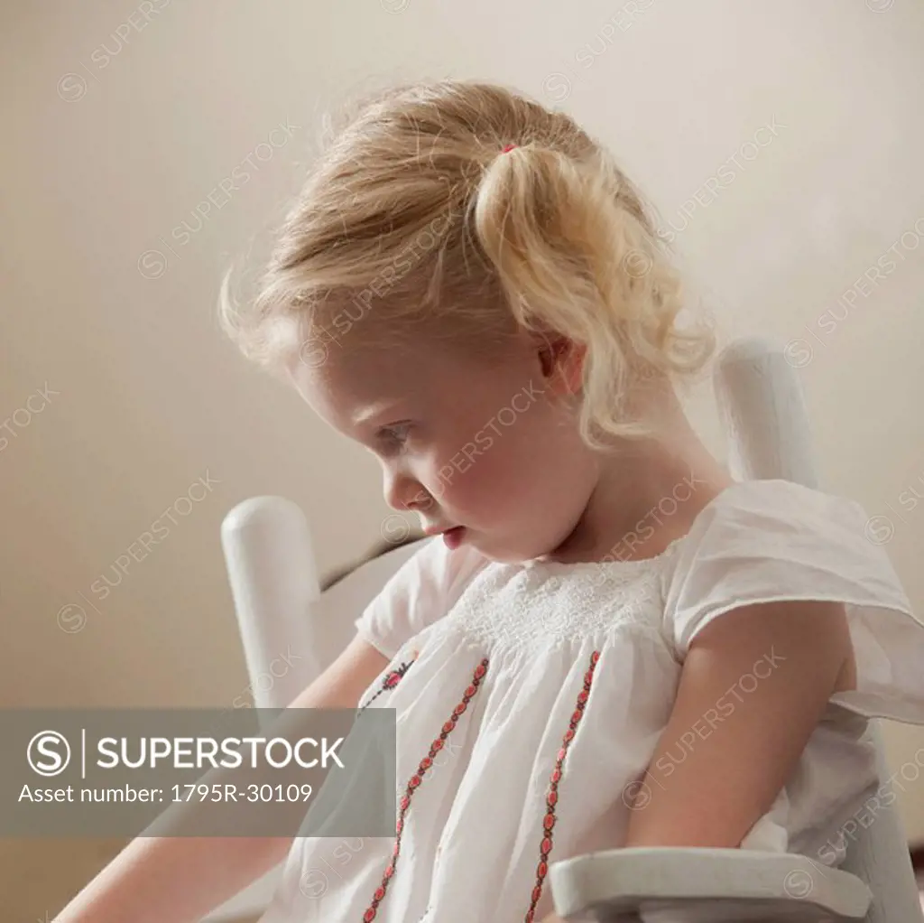 Sad young girl sitting in rocking chair