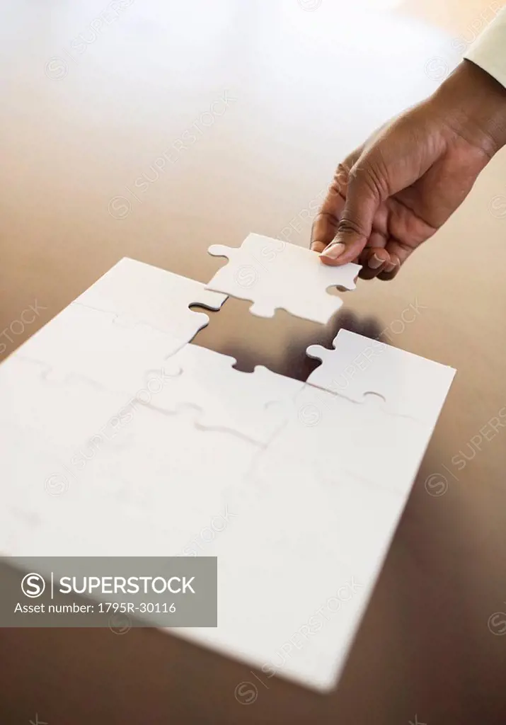 Hand putting last puzzle piece in puzzle