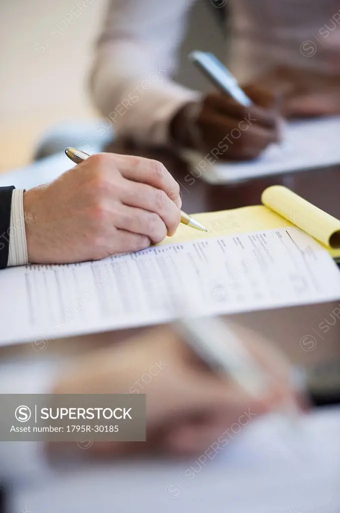 Business people writing notes during business meeting