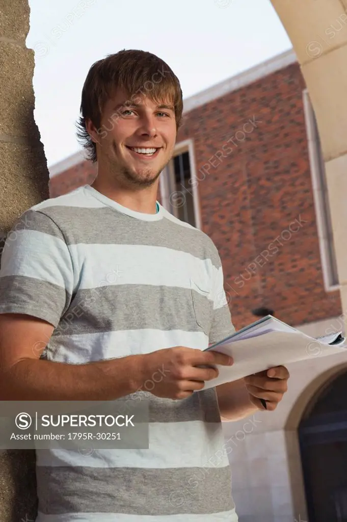 Happy teenage boy holding schoolwork