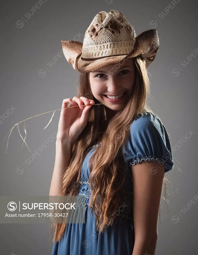 Beautiful long haired cowgirl chewing on grass