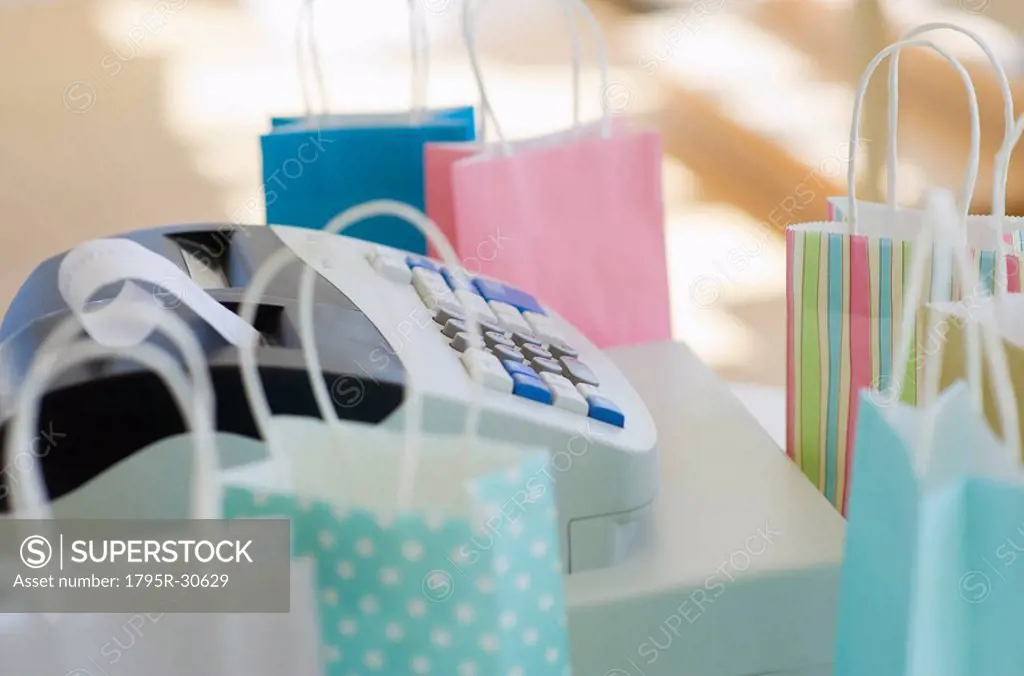 Cash register surrounded by colorful shopping bags