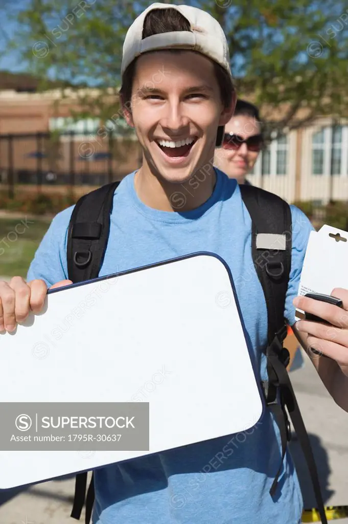 Happy teenage student holding blank whiteboard