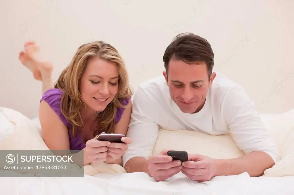 Couple lying on bed while texting