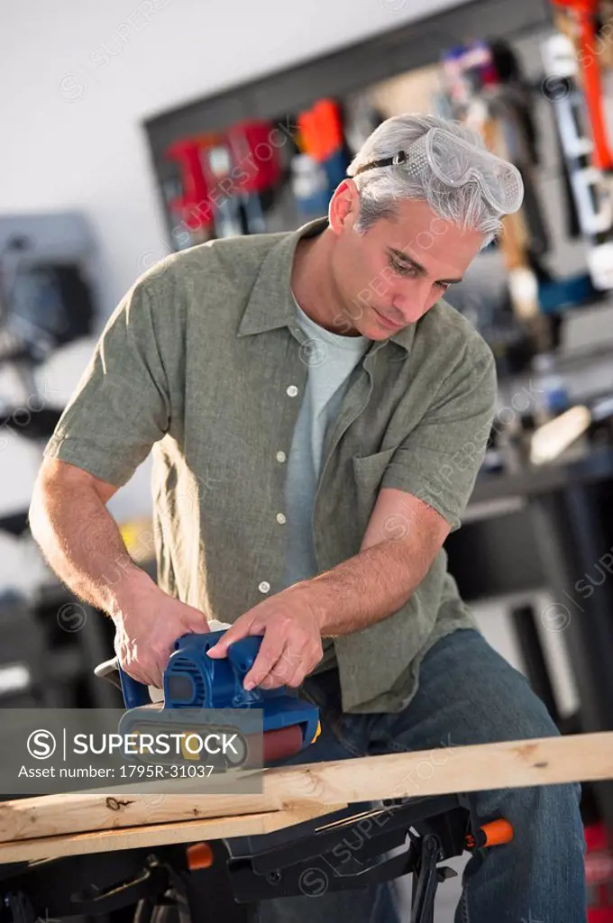 Handyman sanding a piece of wood in workshop