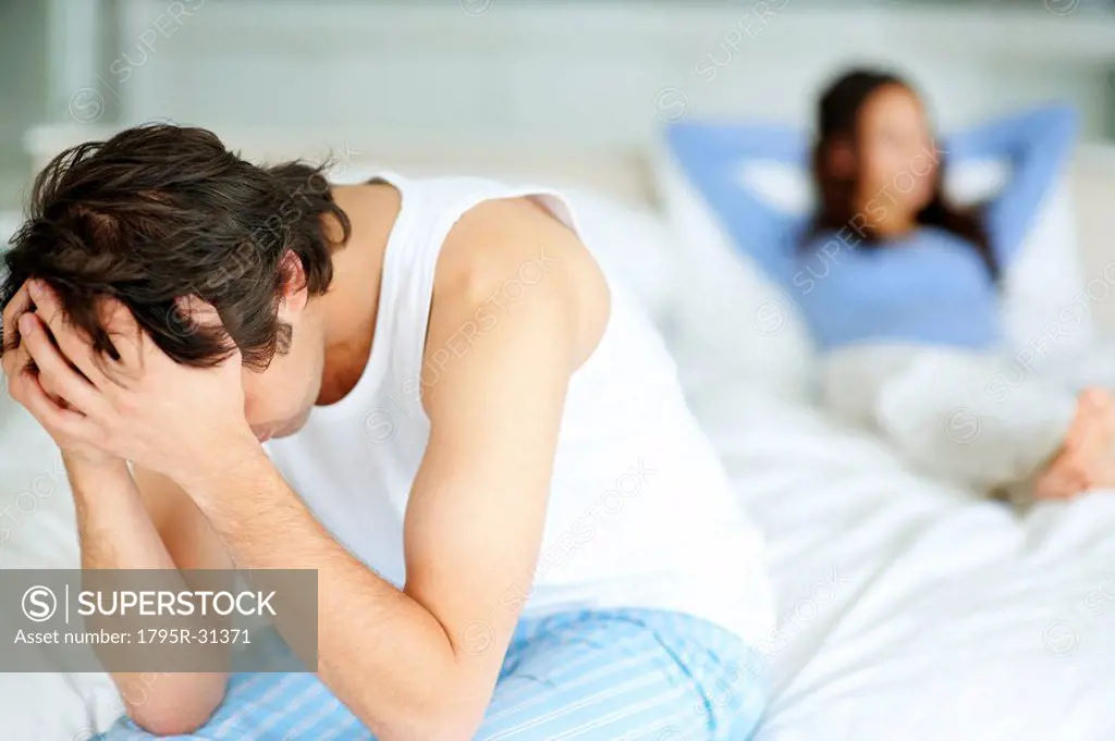 Frustrated man sitting on edge of bed