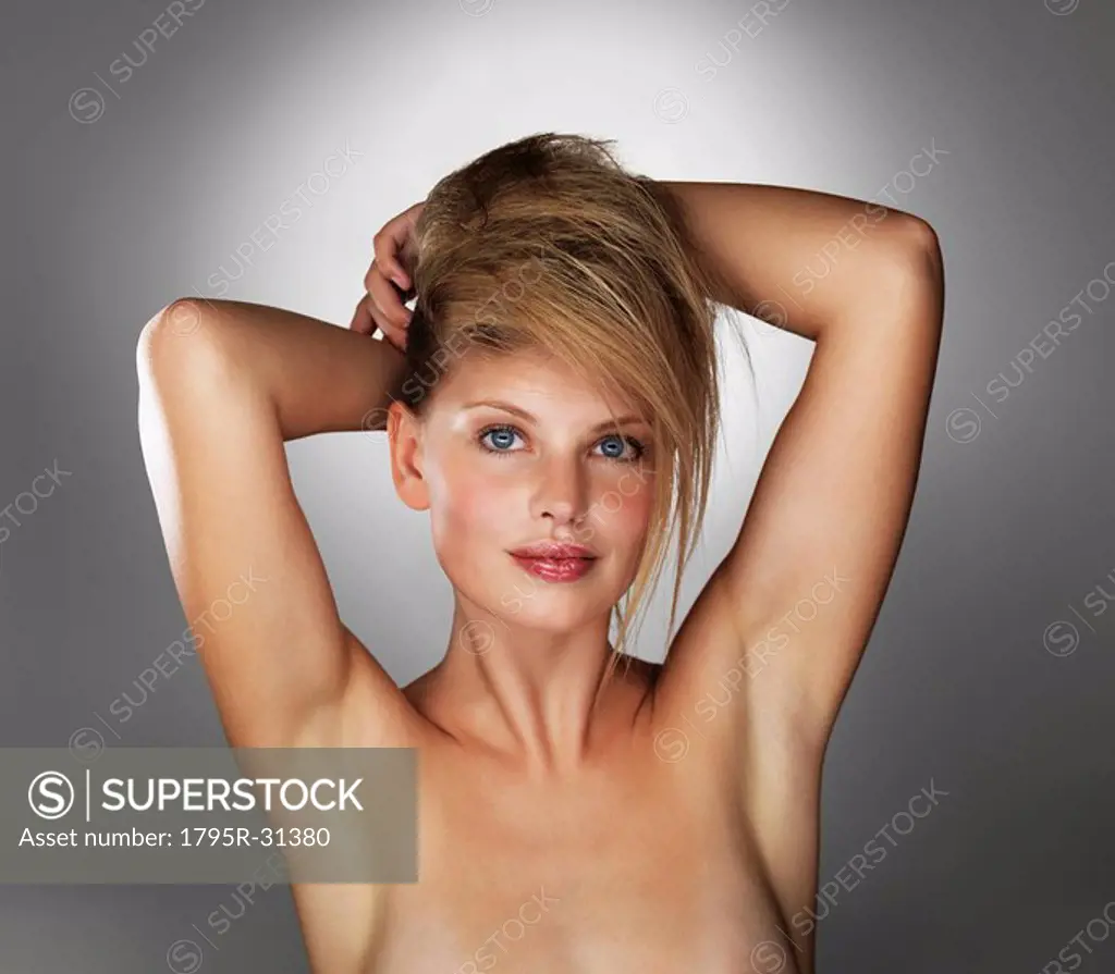 Seductive blond woman with her hands behind her head