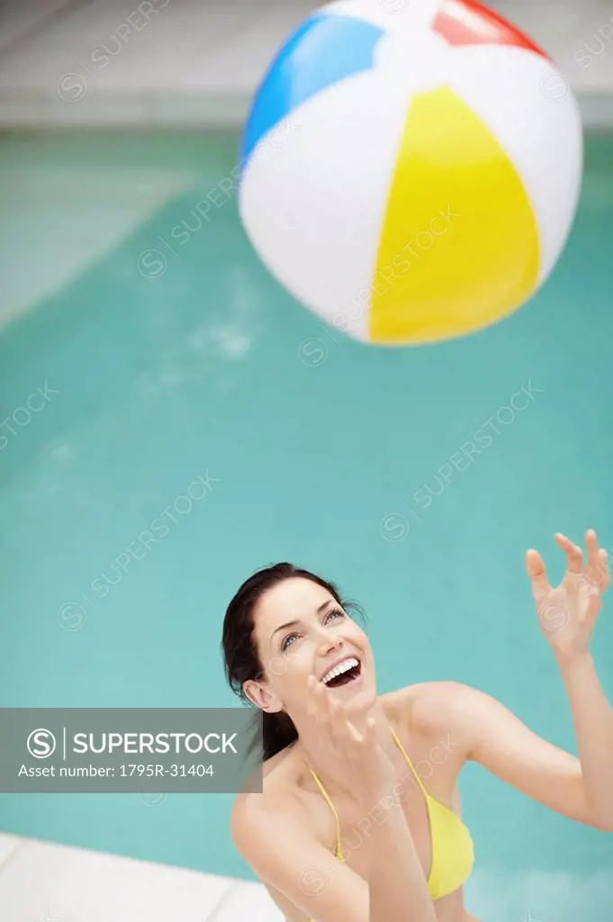 Attractive brunette playing with a beach ball