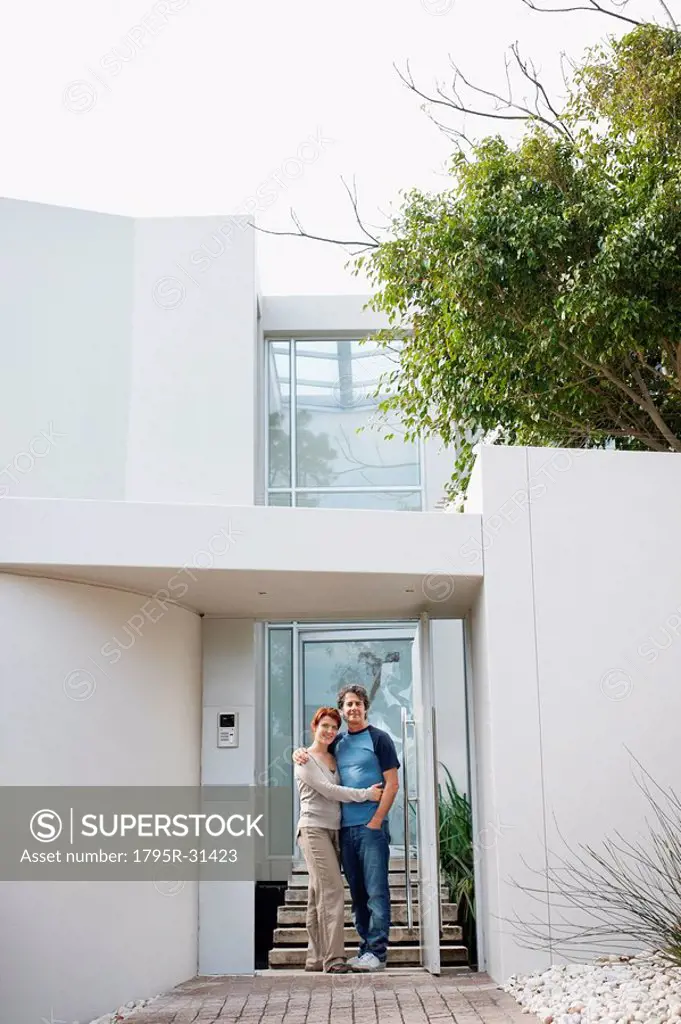 Happy couple embracing in front of their home