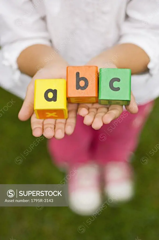 Closeup of girl holding alphabet blocks