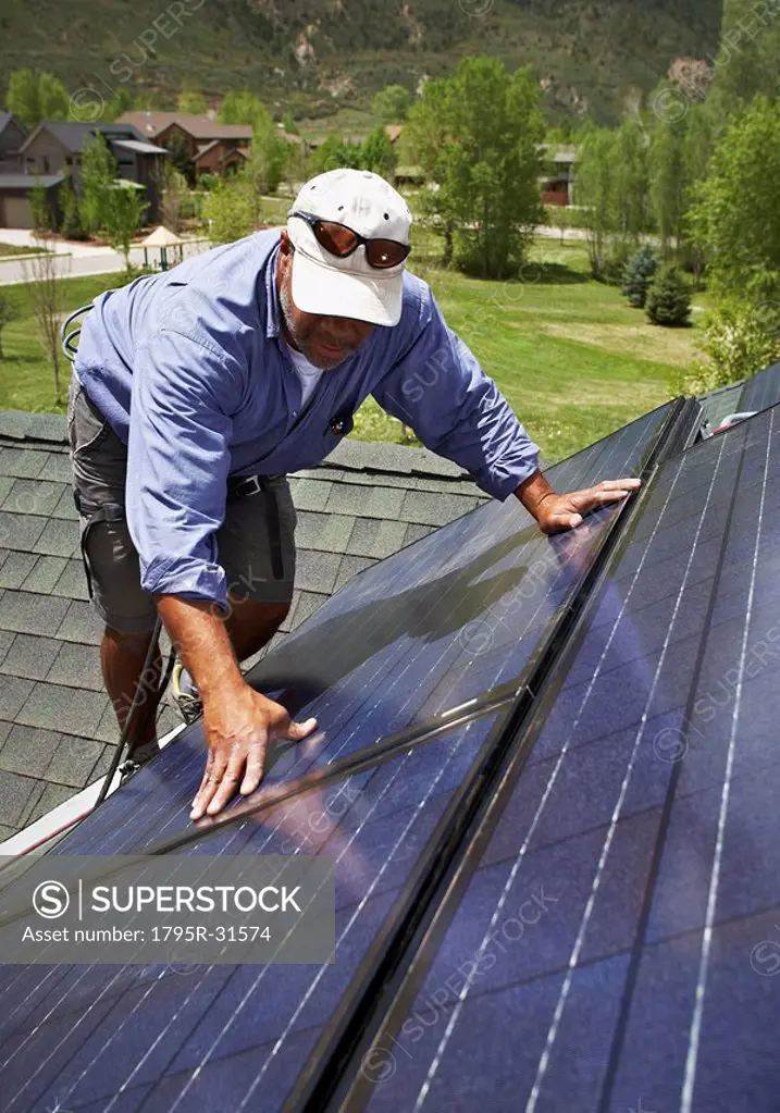 Construction worker installing solar panel on roof