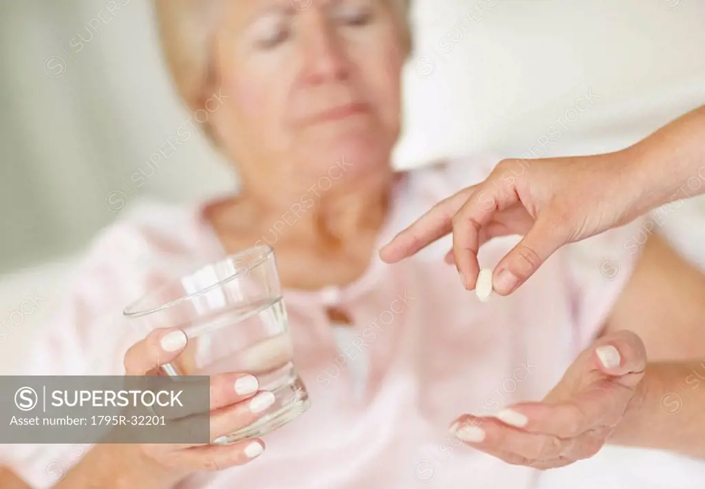 Nurse giving pill to senior woman