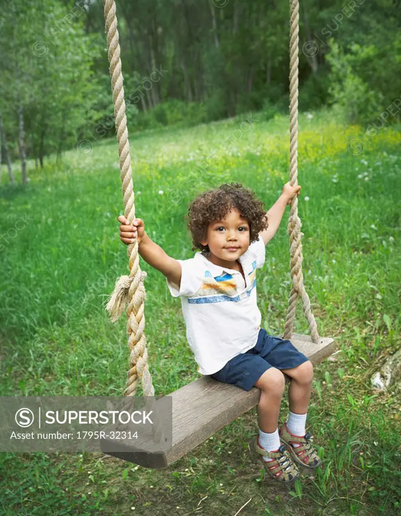 Young child sitting on large outdoor swing