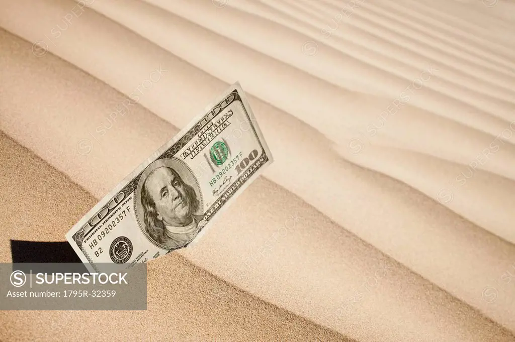 100 dollar bill in sand