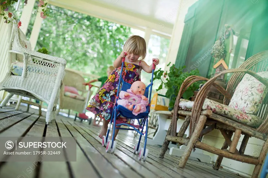 Little girl pushing doll in stroller