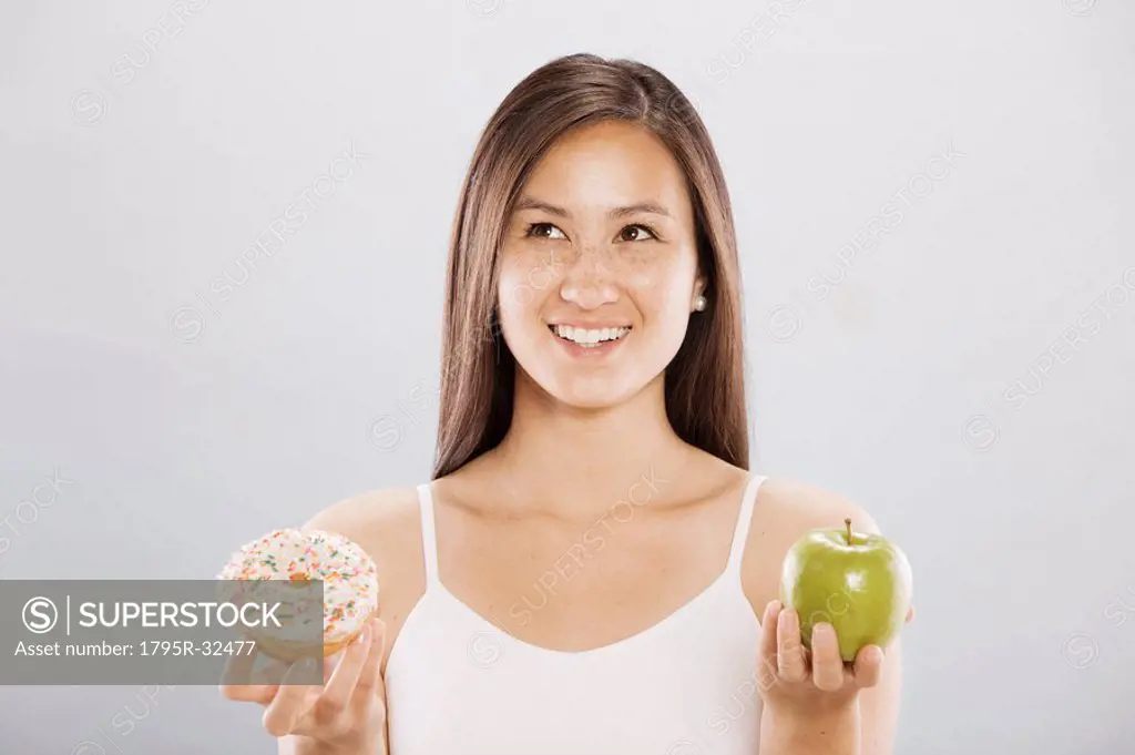 Woman holding an doughnut and an apple