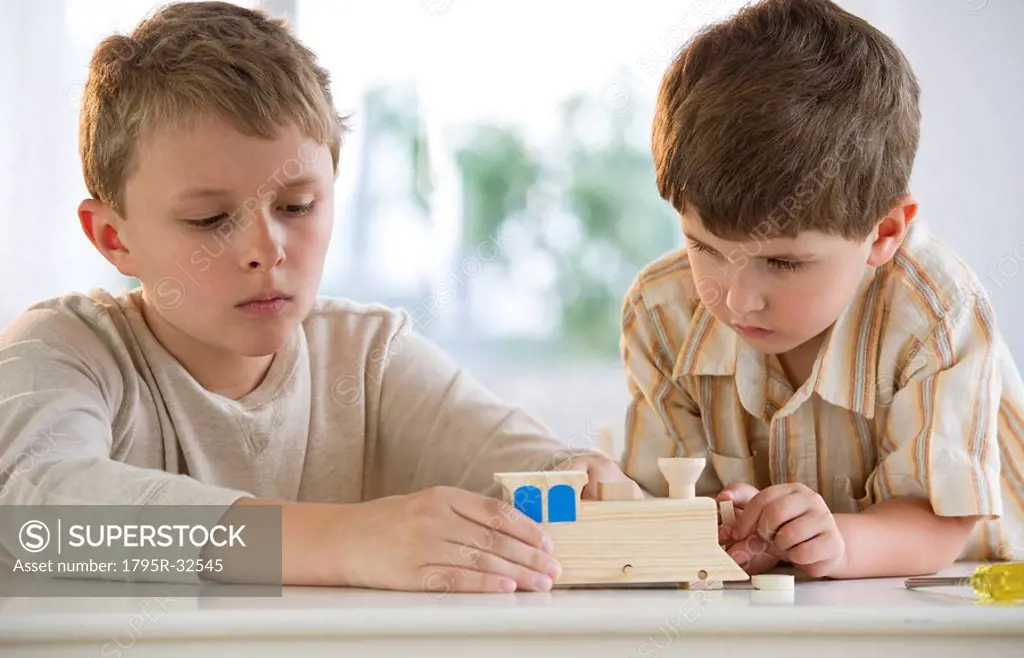 Two young boys building a wooden train