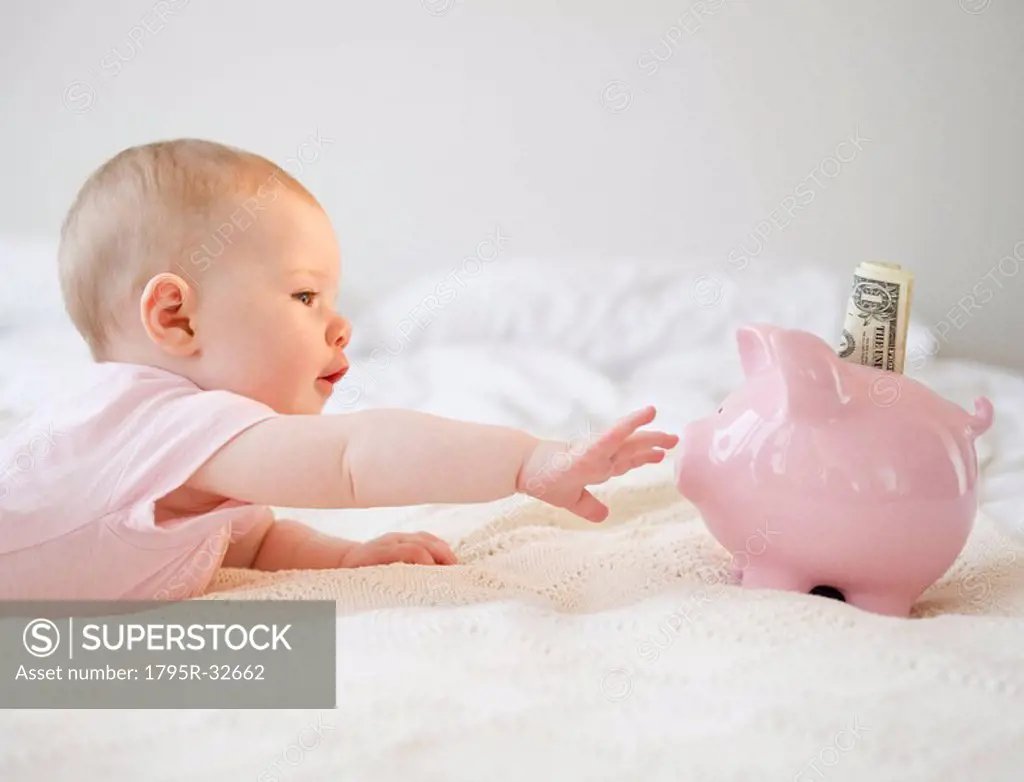 Baby reaching for piggy bank