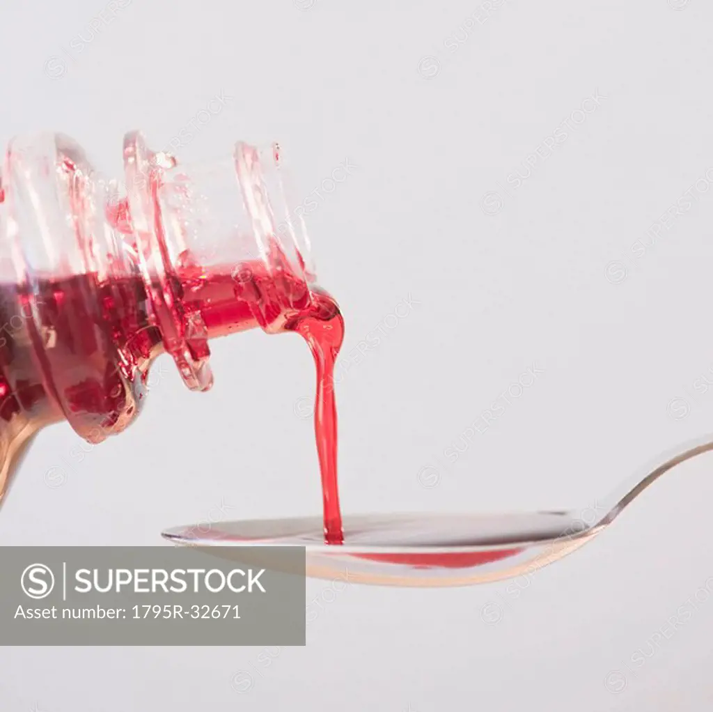 Cough syrup being poured onto spoon