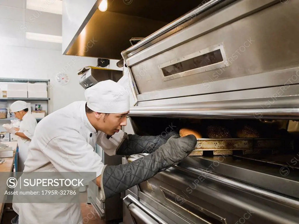 Chef putting bread in oven