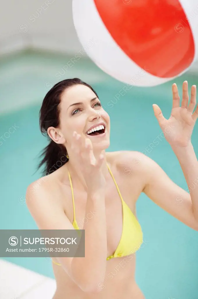 Attractive brunette playing with a beach ball