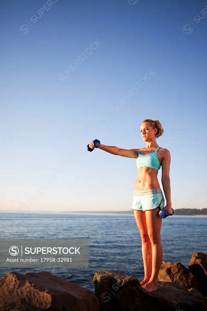 Athletic woman lifting weights outdoors