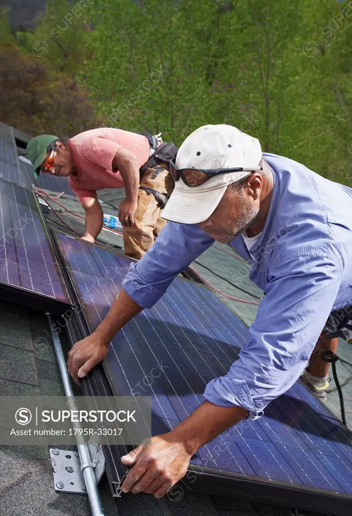 Construction workers installing solar panels on roof