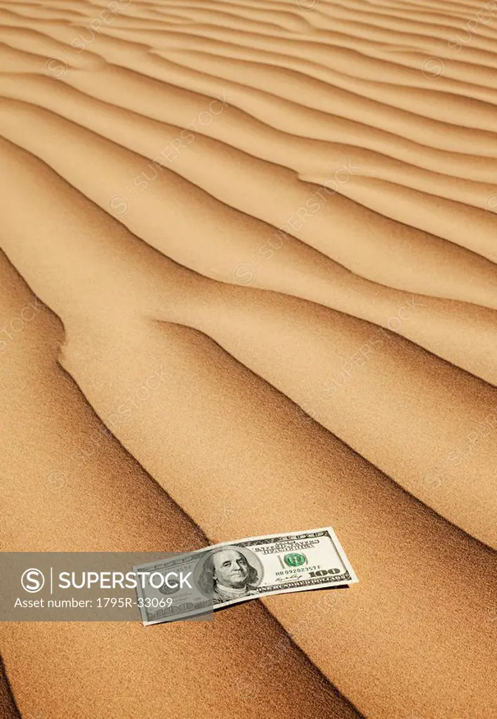 100 dollar bill on sand in desert